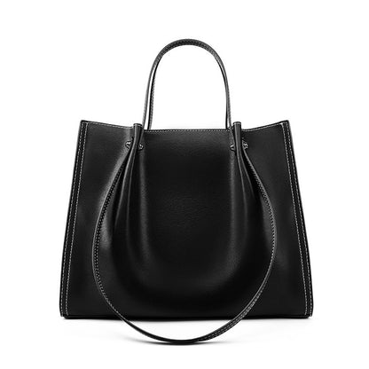 Femme professionnelle portant un sac ordinateur cuir marron rétro en milieu urbain ou bureau

